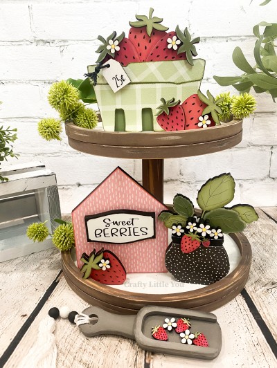 Unfinished kit measures apx. 5.5" tall on the strawberry crate and includes: 
* 1 strawberry crate main piece with attached strawberries
* 1 hanging tag
* 3 sitting strawberries
* 1 house main piece with plaque overlay
* 1 strawberry pot with attached leaves
* 1 small bunch of strawberries
* 6 flowers
* 6 strawberry stem overlays
* Black vinyl