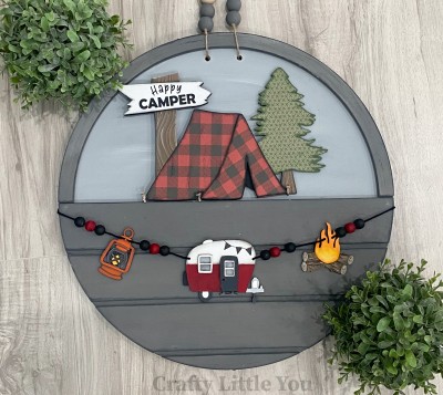 Unfinished kit measures apx. 7" tall and includes wooden MDF: 
* 1 main piece with connected tent, tree, and sign
* 1 tent opening overlay
* 1 sign overlay
* 1 hanging lantern
* 1 hanging camper with door and window overlays
* 1 hanging campfire
* Black vinyl
* 2 pieces Velcro