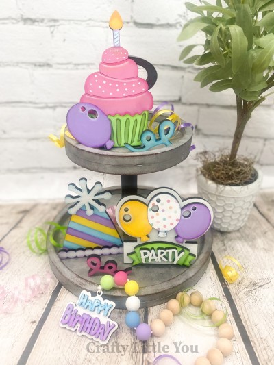 Unfinished kit measures apx. 6.5" tall on the cupcake, and includes wooden MDF: * 1 cupcake with attached candle, * 1 sitting balloon, * 2 confetti wood pieces, * 1 birthday hat, * 1 birthday hat trim overlay, * 1 birthday hat topper overlay, * 1 party sign back piece, * 3 connected balloons, * 1 banner wood overlay, * 1 set of "PARTY" wood letters